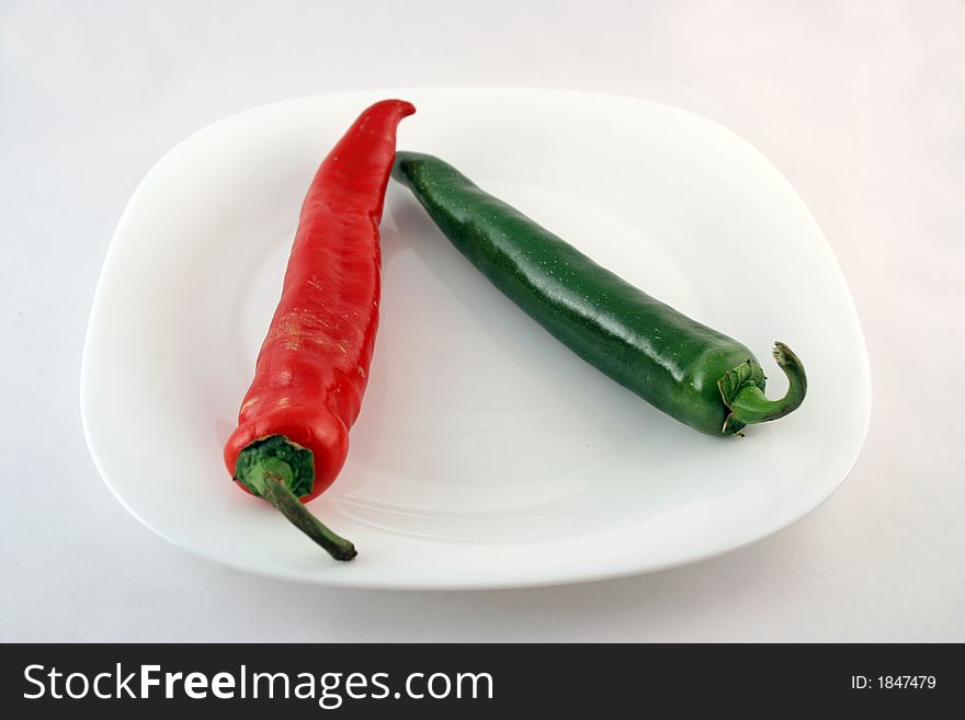 Red and green pepper on a plate on a white background
