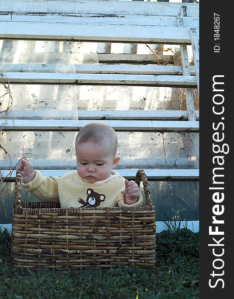 Image of baby boy sitting in a basket in front of some old windows. Image of baby boy sitting in a basket in front of some old windows