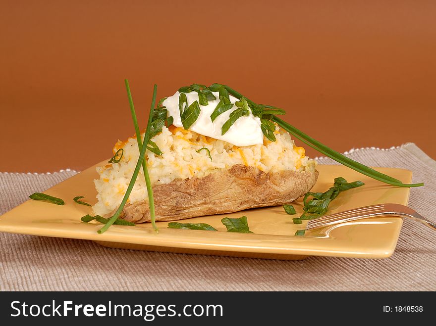 A twice baked potato with chives and sour cream