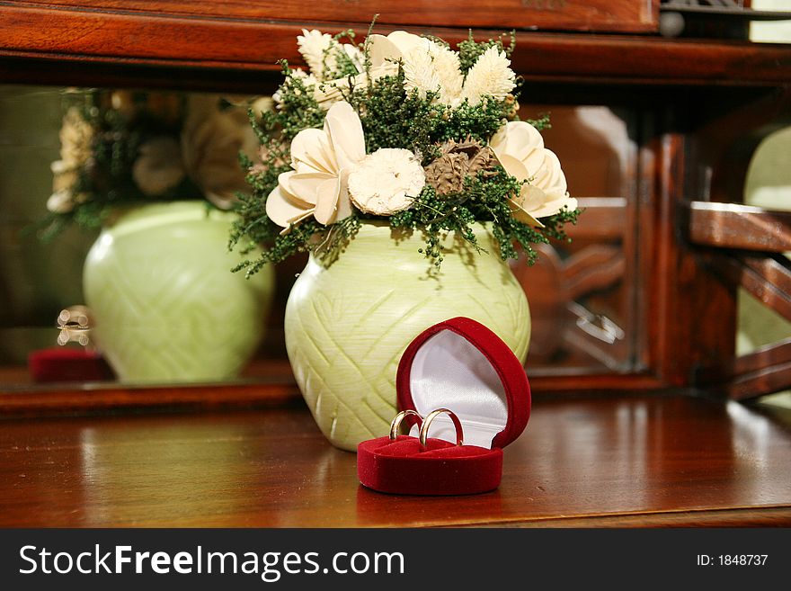 Gold wedding rings in a red casket on a background flowers
