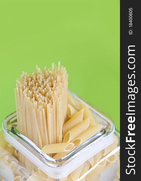 Shaped pasta with spaghetti has a green background