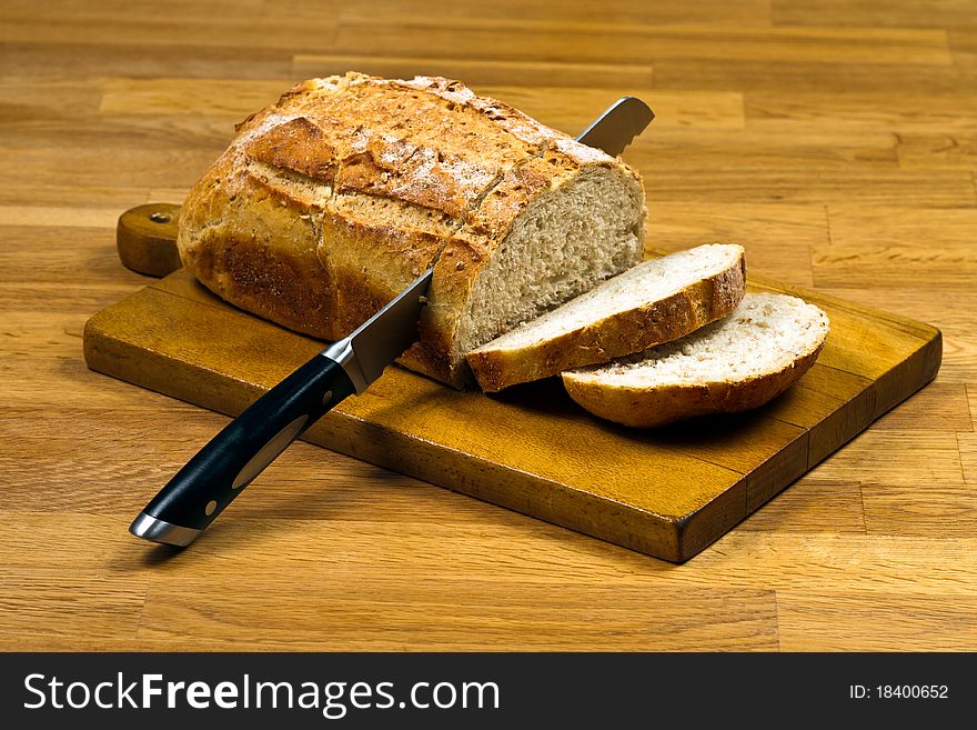 Wooden cutting board with sliced white bread and knife on wooden table. Wooden cutting board with sliced white bread and knife on wooden table