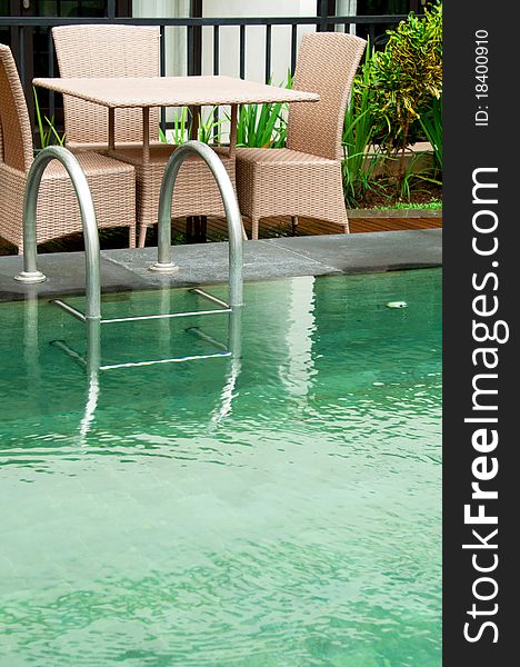 Poolside view of a ladder and wicker furniture. Poolside view of a ladder and wicker furniture