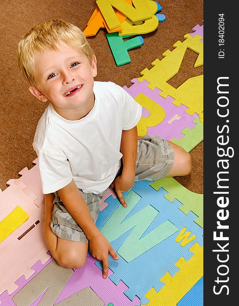 Young blonde boy points to the new letter he has learned from the alphabet. Young blonde boy points to the new letter he has learned from the alphabet.