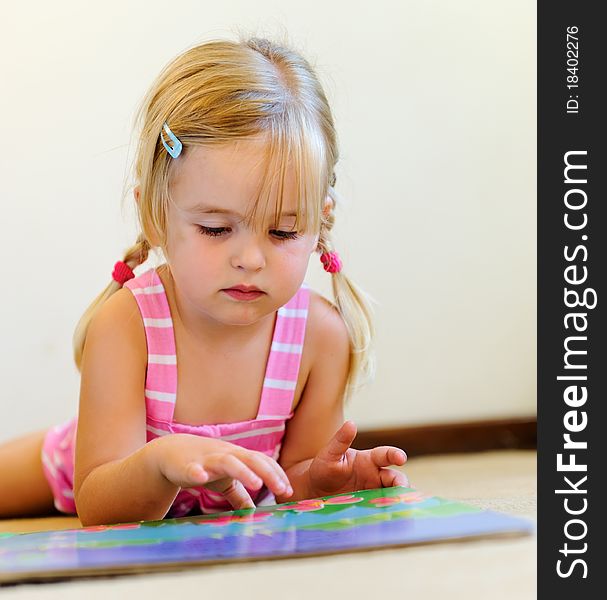 Young adorable blonde girl reads a book on her own. Young adorable blonde girl reads a book on her own