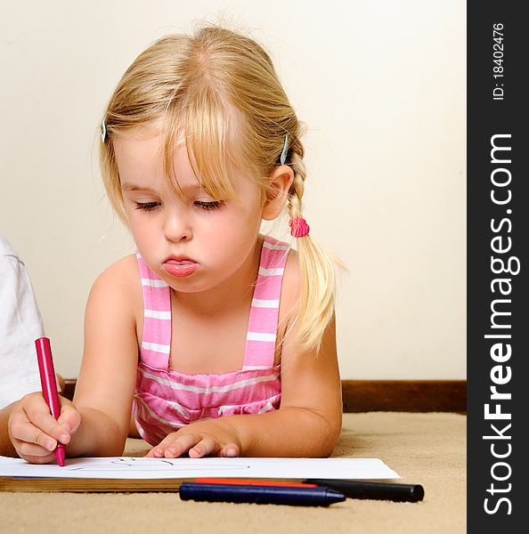 Blonde girl drawing with crayons in school. Blonde girl drawing with crayons in school