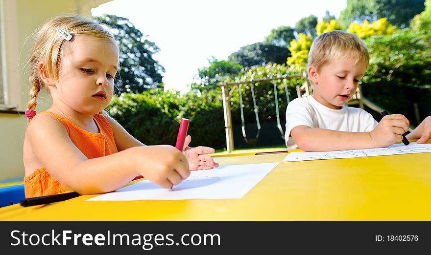 Cute adorable young kids with crayons at an outside playschool. Cute adorable young kids with crayons at an outside playschool