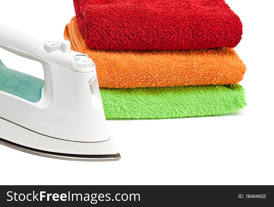 Iron and stacked colorful towels isolated on a white background. Iron and stacked colorful towels isolated on a white background.