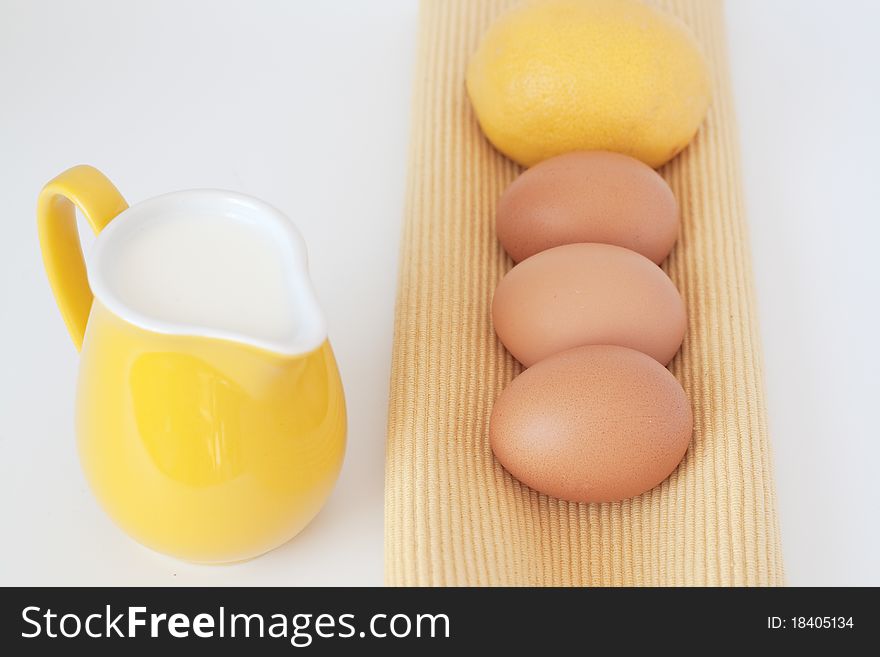 Eggs, milk jug and a lemon on a white background. Eggs, milk jug and a lemon on a white background