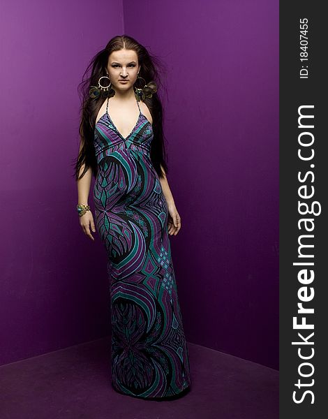 Brunette in a long dress standing in a purple corner. Brunette in a long dress standing in a purple corner