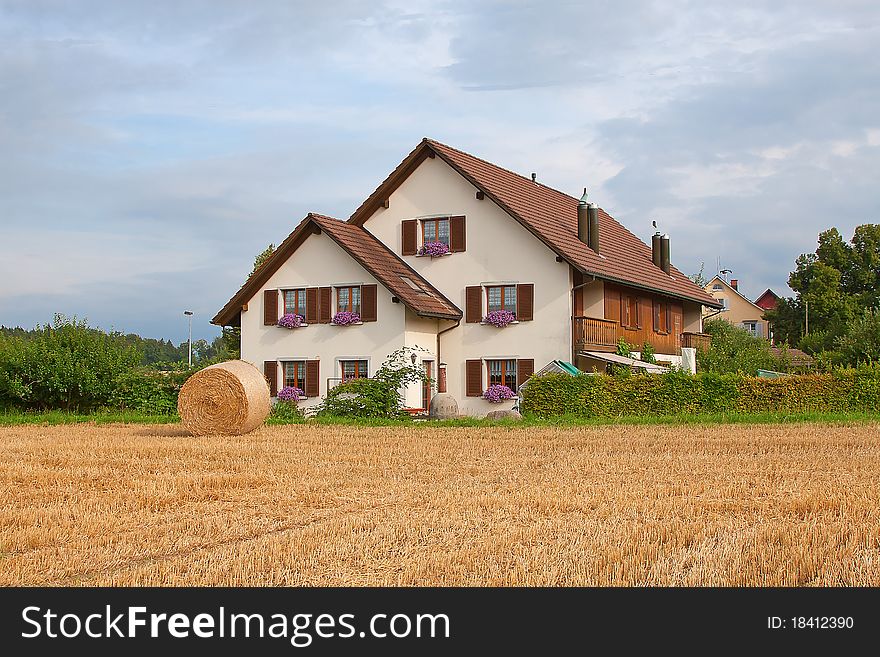 Typical swiss rural landscape with farm house and packed hay