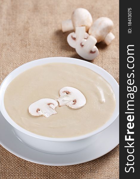 Bowl of mushroom soup with fresh mushrooms and parsley