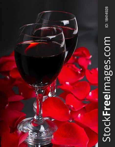 Two glasses of wine with petals of rose