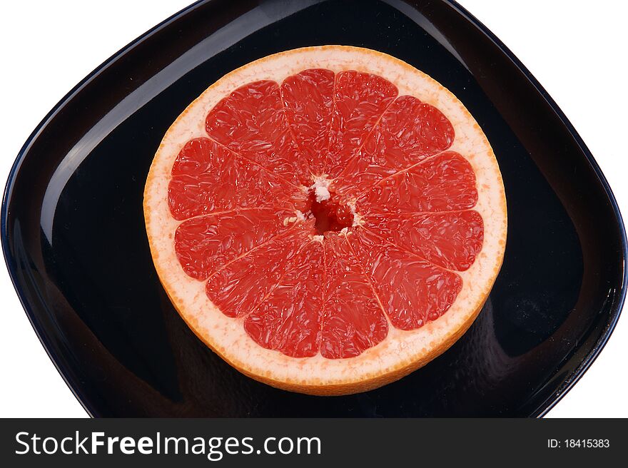 Ripe red grapefruit. The cut fruit on a dark blue plate