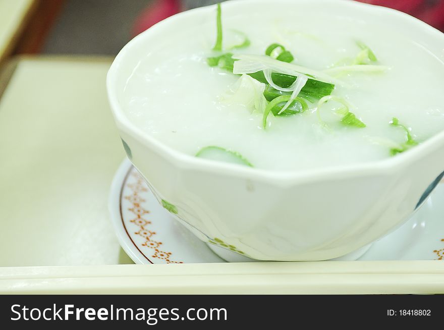 Rice porridge, or jook in white bowl with chopsticks. Rice porridge, or jook in white bowl with chopsticks