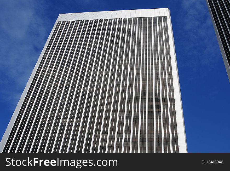 Very tall building looking upward, blue sky with light white clouds, modern architecture. Very tall building looking upward, blue sky with light white clouds, modern architecture