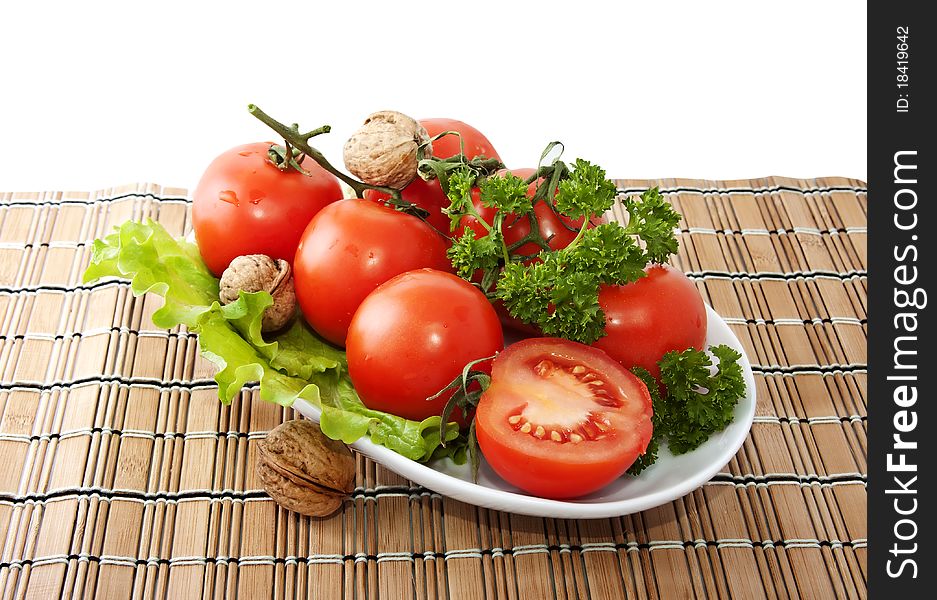 Bunch of tomatoes and lettuce on the surface of woven straw