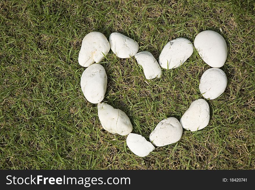 White stones in heart shape on green grass. White stones in heart shape on green grass