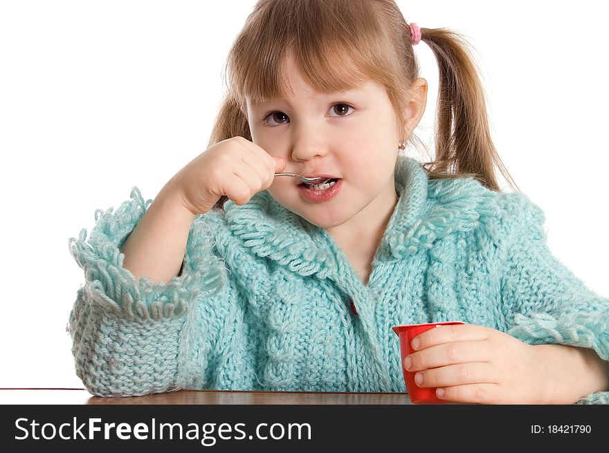 The little girl eats yoghurt on white