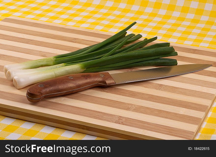 Green onion and knife on a wooden tray