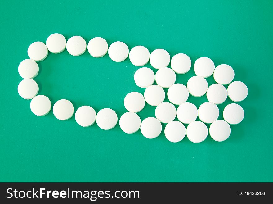 White pills form capsule shape isolated on green background