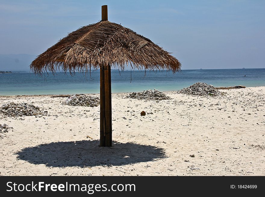 Palm umbrella on the white sand beach