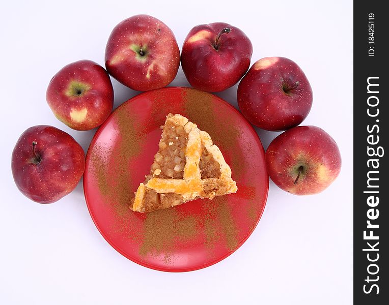 Apple Pie - a slice on a plate decorated with cinnamon and some red apples