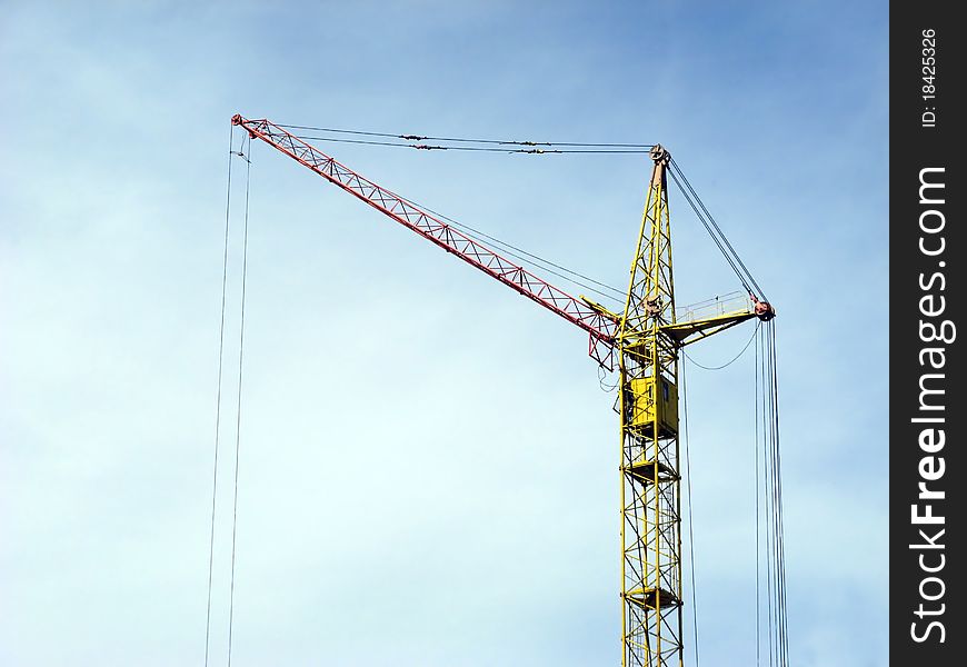 Silhouette of lifting crane against a background of blue sky