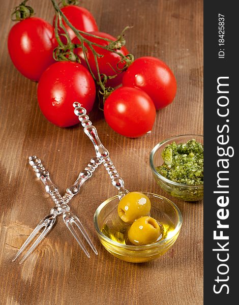 Snacks with green olives, fresh tomato and pesto sauce on wooden table. Snacks with green olives, fresh tomato and pesto sauce on wooden table
