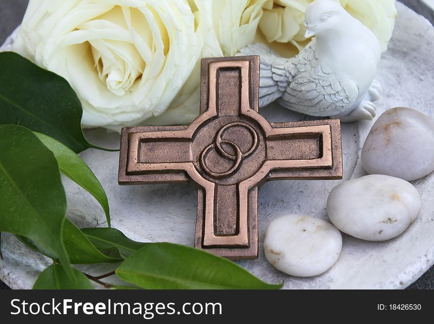 Bronze cross in front of a rose