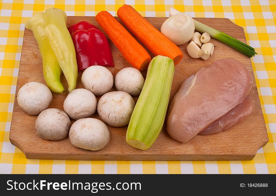 Chicken breast, green onion, red pepper, yellow pepper,zucchini, mushrooms and garlic on a wooden tray. Chicken breast, green onion, red pepper, yellow pepper,zucchini, mushrooms and garlic on a wooden tray