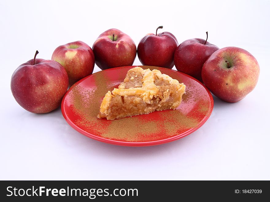 Apple Pie - a slice on a plate decorated with cinnamon and some red apples