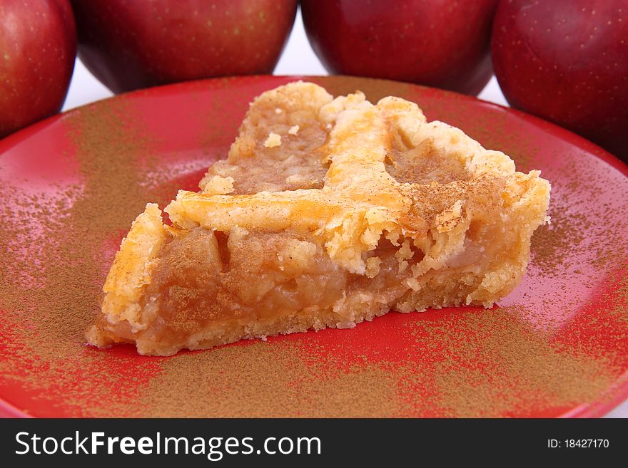 Apple Pie - a slice on a plate decorated with cinnamon and some red apples