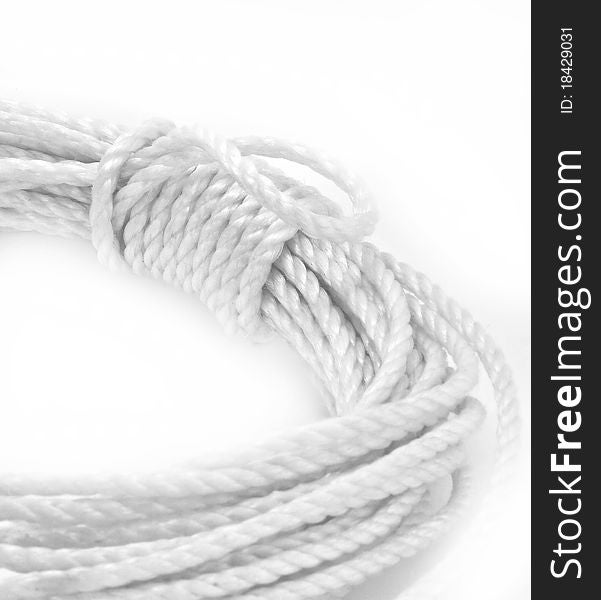 White rope is coiled on white background; closeup of wrapped coil. White rope is coiled on white background; closeup of wrapped coil