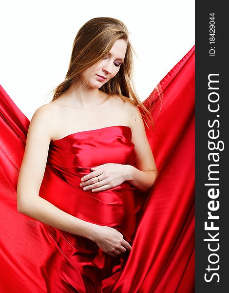 A beautiful young pregnant woman in red on a white background