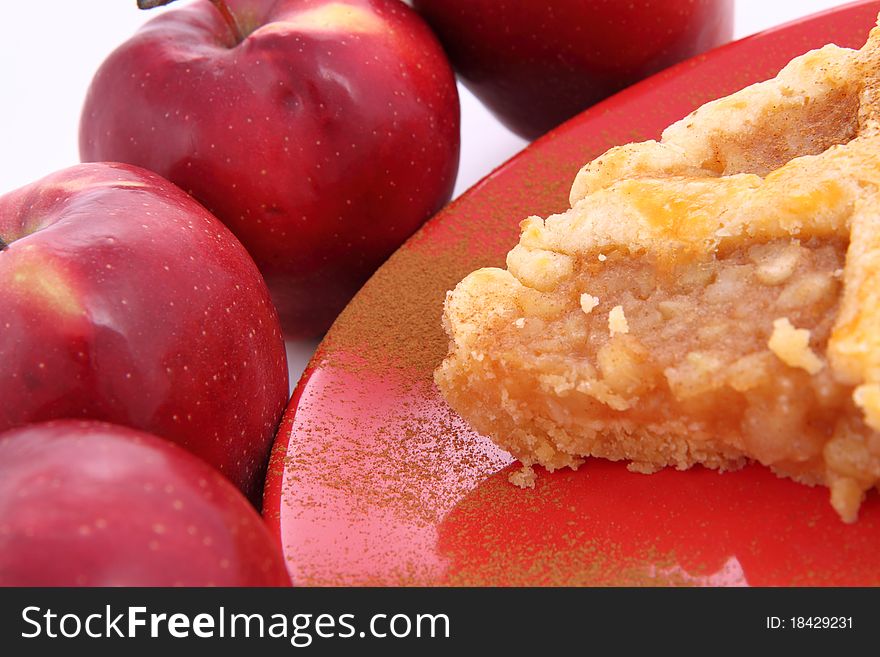 Apple Pie - a slice on a plate decorated with cinnamon and some red apples