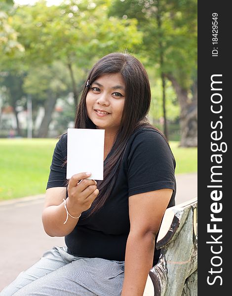Women sitting in the park and hold a white card. Women sitting in the park and hold a white card.