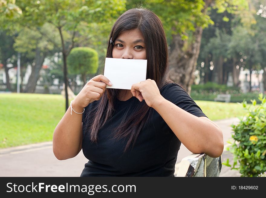 Women sitting in the park and hold a white card. garden park