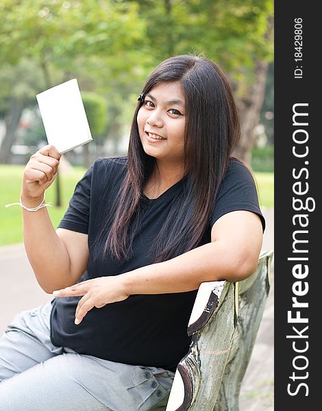 Women in the garden and holding a white card.