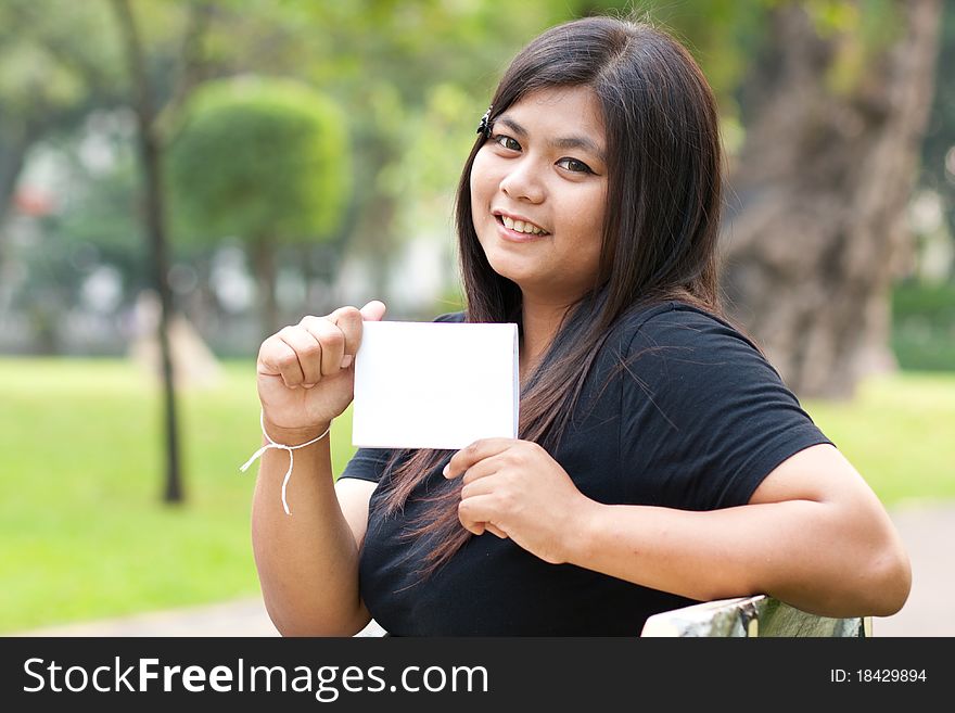 Women sitting in the park and hold a white card. Women sitting in the park and hold a white card.