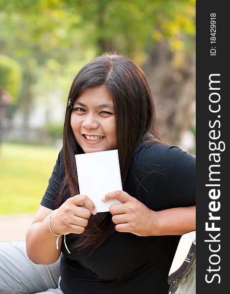 Women sitting in the park and hold a white card. Women sitting in the park and hold a white card.