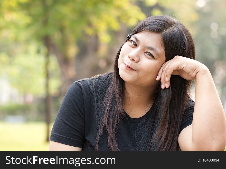 Woman sitting in park smiling towards you. Woman sitting in park smiling towards you.