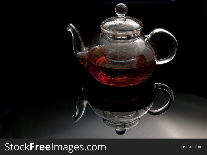 Glass teapot with the made tea on a glass surface. Glass teapot with the made tea on a glass surface