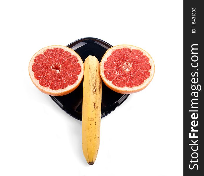 Ripe red grapefruit (slice the fruit) and a banana on a dark blue plate. Ripe red grapefruit (slice the fruit) and a banana on a dark blue plate