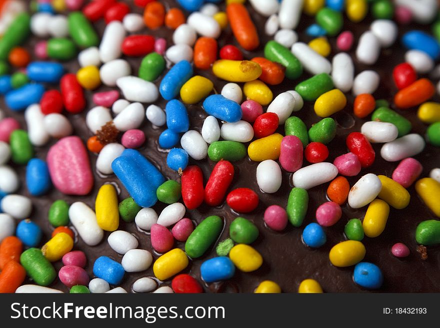 Multicoloured truffle candy on dark chocolate, macro shoot. Multicoloured truffle candy on dark chocolate, macro shoot