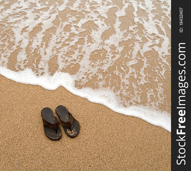 Beach sandles or tongs on a sandy beach with lots of background copyspace