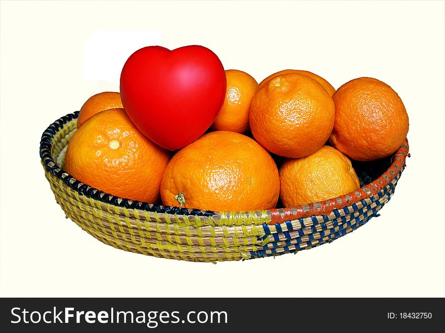 A full of Vitamin C, fun & vivid picture of a basket of agrums (orange + tangerine), with a red shiny heart among them, looking like another sibling fruit ready to be picked. Fruits are in a straw basket, with yellow and blue stripes. Isolated on white. A full of Vitamin C, fun & vivid picture of a basket of agrums (orange + tangerine), with a red shiny heart among them, looking like another sibling fruit ready to be picked. Fruits are in a straw basket, with yellow and blue stripes. Isolated on white.