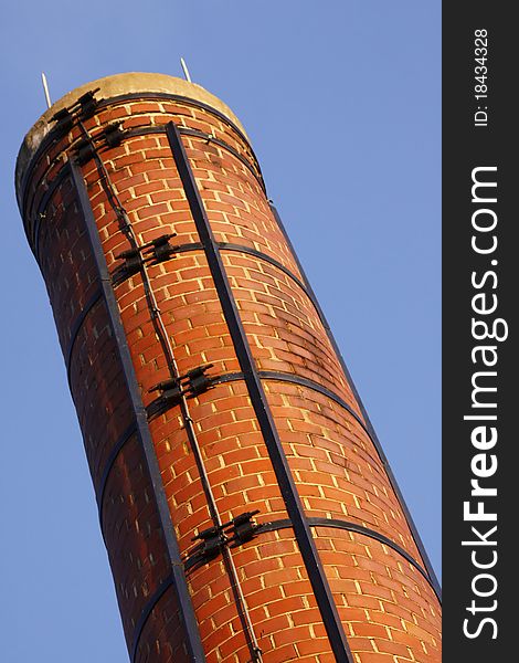 An old red brick chimney smoke stack against a blue sky at Plattsburgh Community College in upstate New York State.