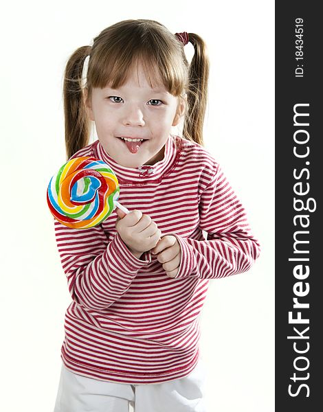 Little girl eating a lollipop atd sticking out tongue. Little girl eating a lollipop atd sticking out tongue