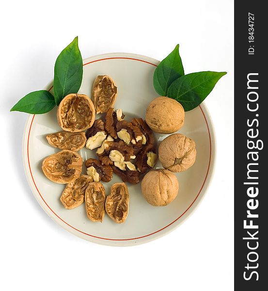 Chopped and whole walnuts on a plate. White background.